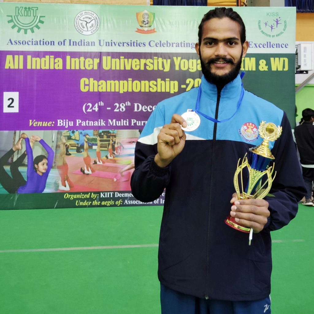 Coach Suresh Kumar holding his All India Inter-University Yoga Championship Silver Medal and trophy
